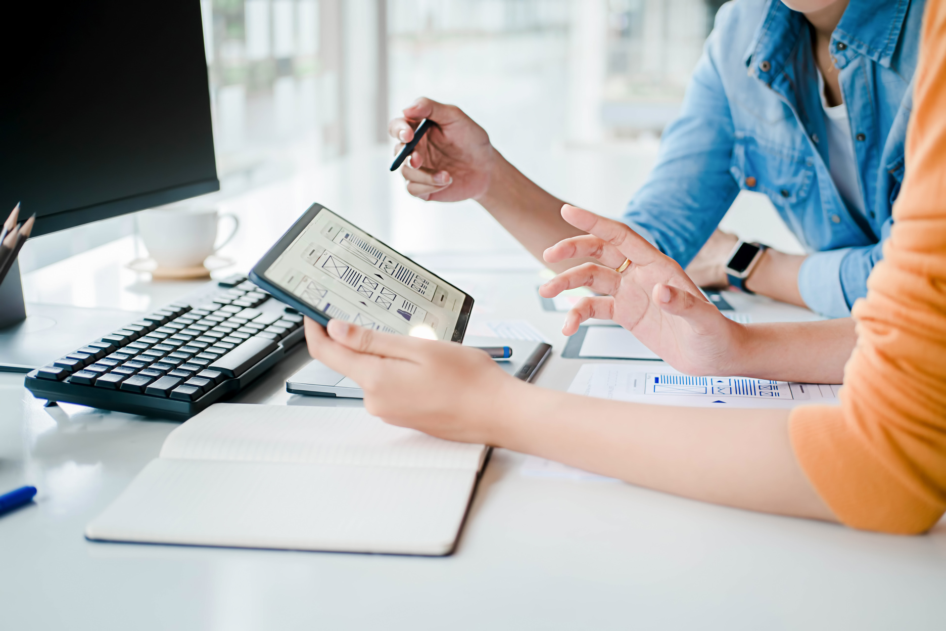 two people sitting at a table with a laptop and pen